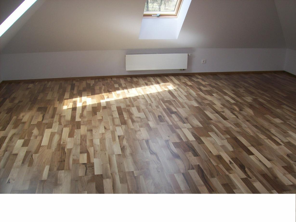 Parkiet ułożony w jodełkę francuską w jasnym pokoju na poddaszu, z widocznym oknem dachowym i grzejnikiem na ścianie.
