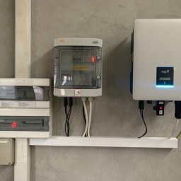 HORIZONTAL ENERGY RAFAŁ WITCZAK - Rozdzielnice elektryczne i inwerter FOX w instalacji w Nowych Skalmierzycach, widoczne kable i przewody. Czerwona dioda sygnalizacyjna na jednej z rozdzielnic.