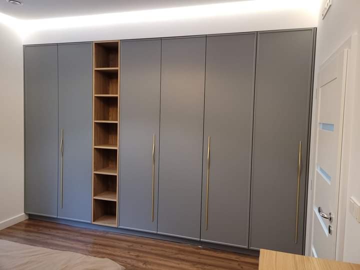 Szara zabudowa szafy wnękowej z otwartą półką z naturalnego drewna, podświetlenie LED sufitowe, parkiet na podłodze.