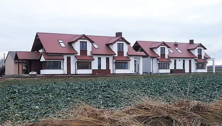 Kompleks nowo wybudowanych domów jednorodzinnych z czerwonymi dachami w Nysie, widok z pola uprawnego w pochmurny dzień.