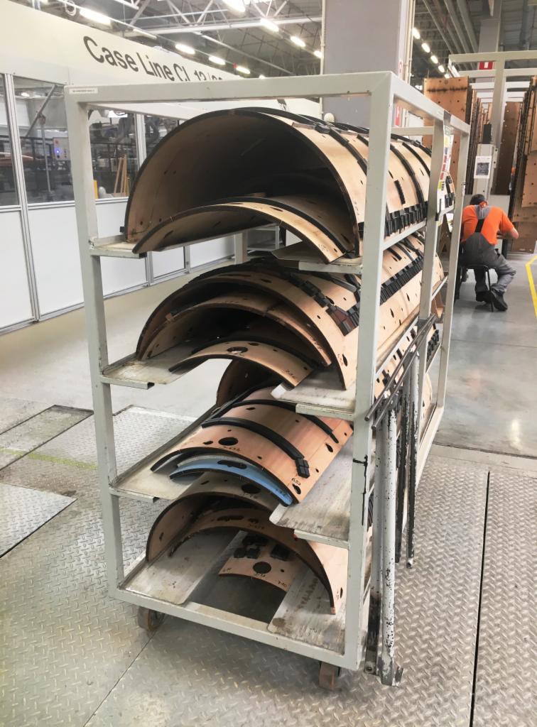 Wózek transportowy z półkolistymi elementami konstrukcyjnymi z wycięciami, prawdopodobnie prefabrykaty do budowy hal, widoczne oznaczenia numeryczne na elementach.