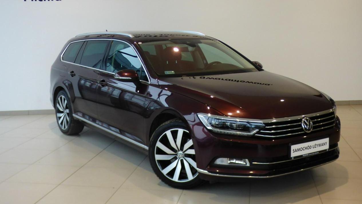 Bordowy Volkswagen Passat Variant na ekspozycji, widoczne felgi z wzorem turbiny i tabliczka 'Samochód Używany'.