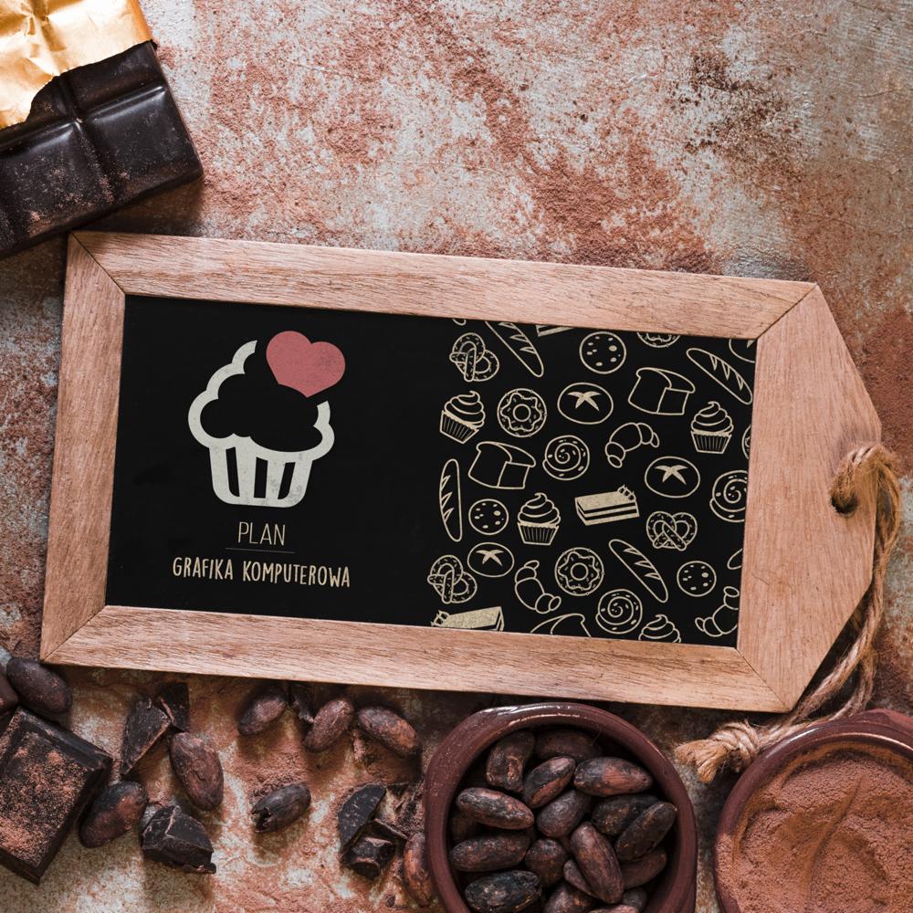 Tablica z drewnianą ramką prezentująca plan grafiki komputerowej z ikoną babeczki z sercem i rysunkami pieczywa, otoczona czekoladą, ziarnami kakaowca i kakao w proszku.