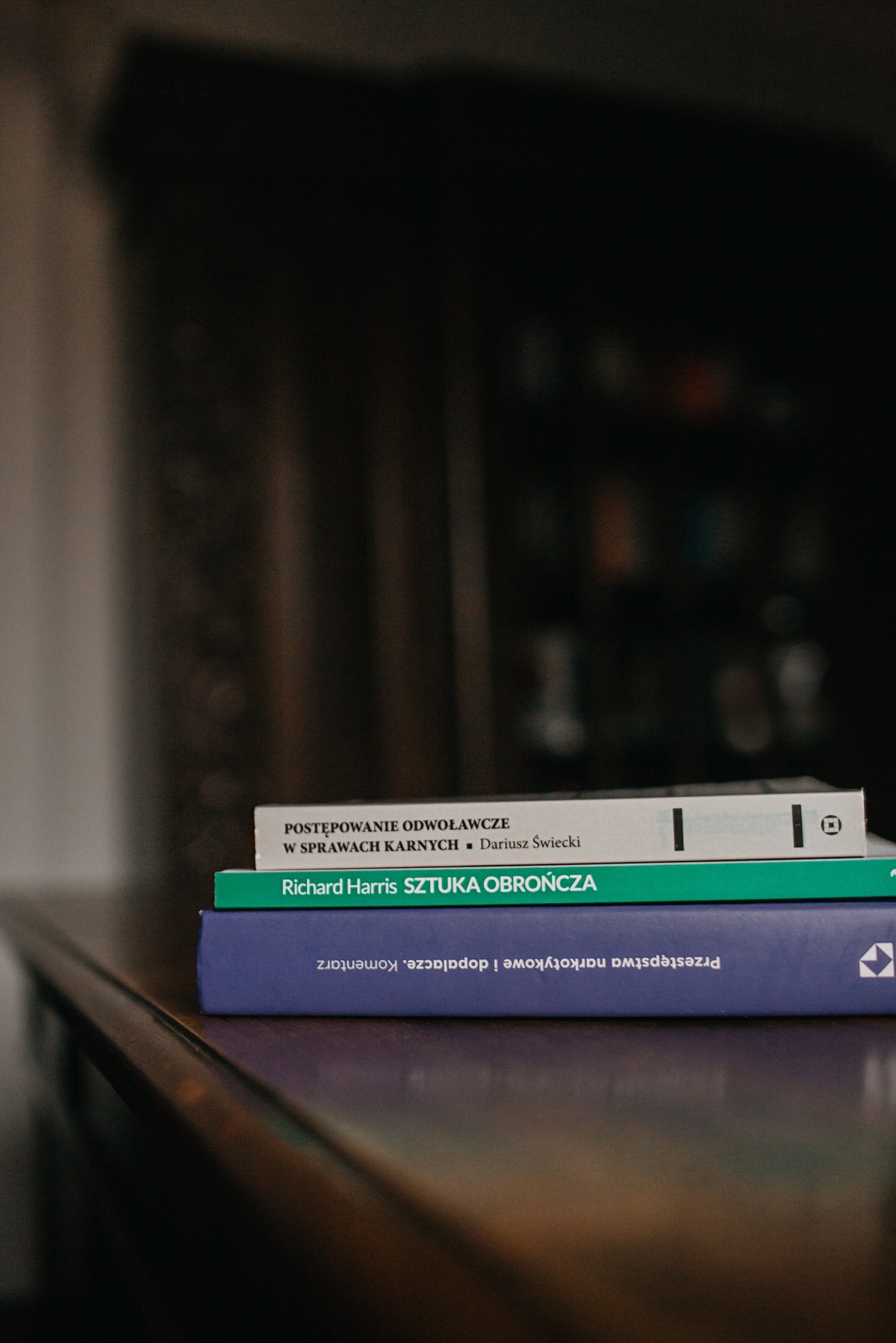 Stos książek prawniczych: 'Postępowanie odwoławcze w sprawach karnych', 'Sztuka obrończa' Richarda Harrisa i komentarz do przestępstw narkotykowych.