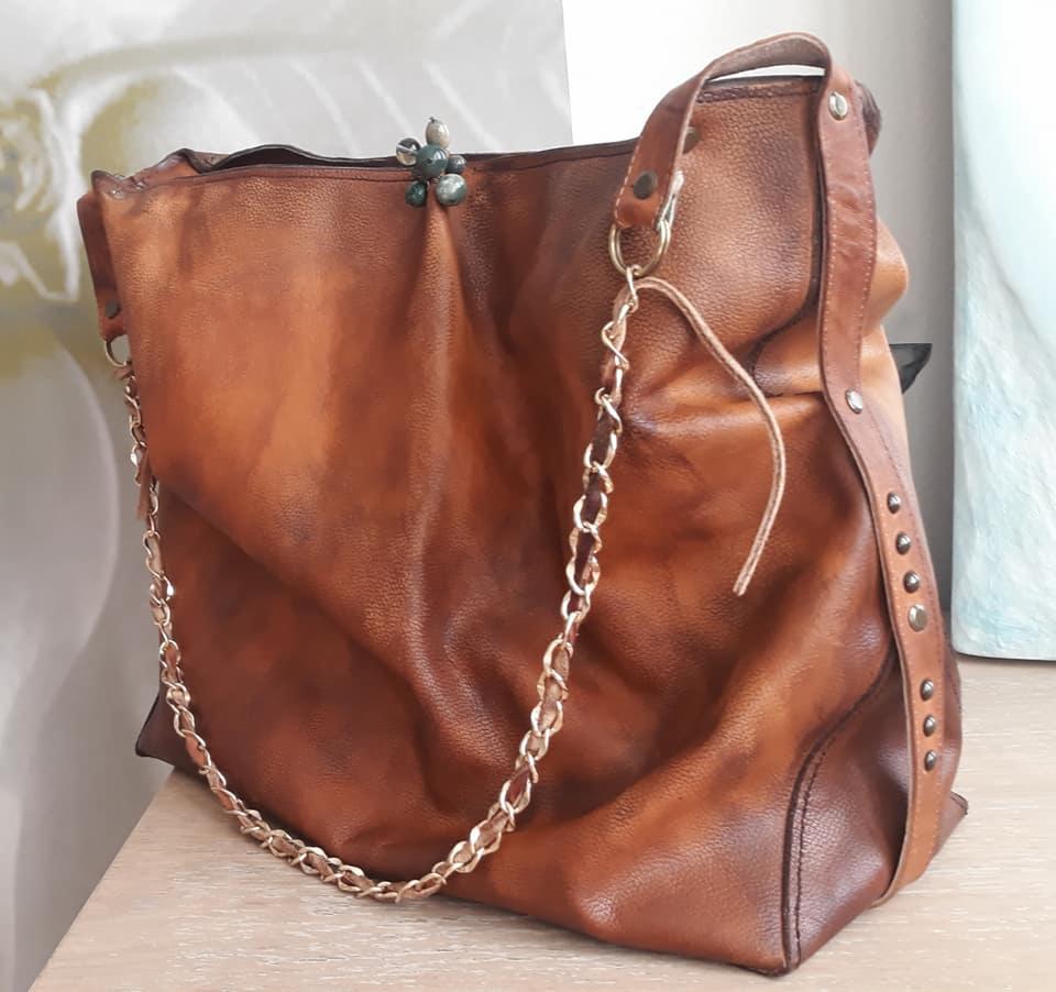 Brązowa skórzana torba typu shopper z łańcuszkiem i ozdobnym zapięciem z kamieni.