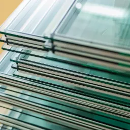 Stos pakietów szyb zespolonych z aluminiowymi ramkami dystansowymi, widoczne warstwy szkła i uszczelniaczy.