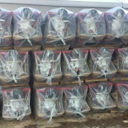 HcLIft - Paleta z chińskimi wózkami widłowymi, każdy zapakowany w przezroczystą folię, widoczne czerwone elementy konstrukcyjne i czarne koła, przygotowane do transportu.