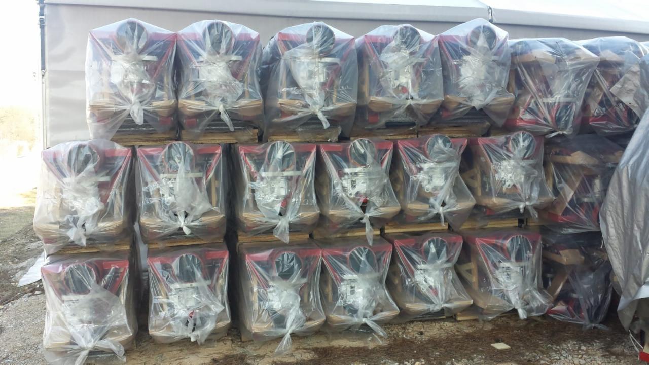 Paleta z chińskimi wózkami widłowymi, każdy zapakowany w przezroczystą folię, widoczne czerwone elementy konstrukcyjne i czarne koła, przygotowane do transportu.