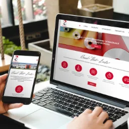 Responsywna strona internetowa firmy Samdex wyświetlana na laptopie i smartfonie, widoczne menu, logo i hasło 'Bond That Lasts' na obu urządzeniach, ujęcie z perspektywy osoby przeglądającej stronę...