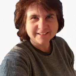 Portret uśmiechniętej kobiety z brązowymi włosami w szarej bluzce, na jasnym tle.