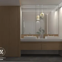 Nowoczesna aranżacja łazienki w Lesznie: podwójna umywalka nablatowa, drewniane szafki pod umywalką, duże lustro z oświetleniem LED, wiszące lampy w kolorze złota, minimalistyczny design.