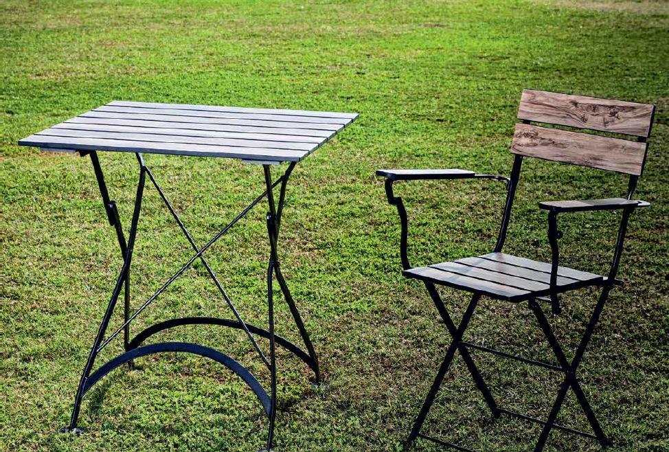 Stół i krzesło ogrodowe z czarnymi metalowymi ramami i drewnianymi elementami blatu i siedziska, ustawione na trawniku.
