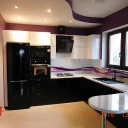 Nowoczesna kuchnia w czarno-białej kolorystyce z blatem z dekoracyjnym motywem fioletowych fal, oświetleniem punktowym i zaokrąglonym półwyspem.