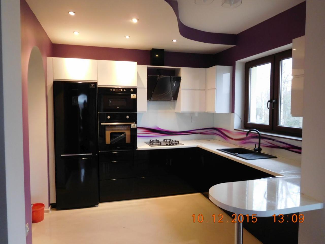 Nowoczesna kuchnia w czarno-białej kolorystyce z blatem z dekoracyjnym motywem fioletowych fal, oświetleniem punktowym i zaokrąglonym półwyspem.