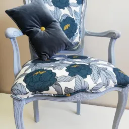Odrestaurowane krzesło w stylu ludwikowskim z nową tapicerką w kwiaty i poduszką z guzikiem, pomalowane na jasnoszaro.