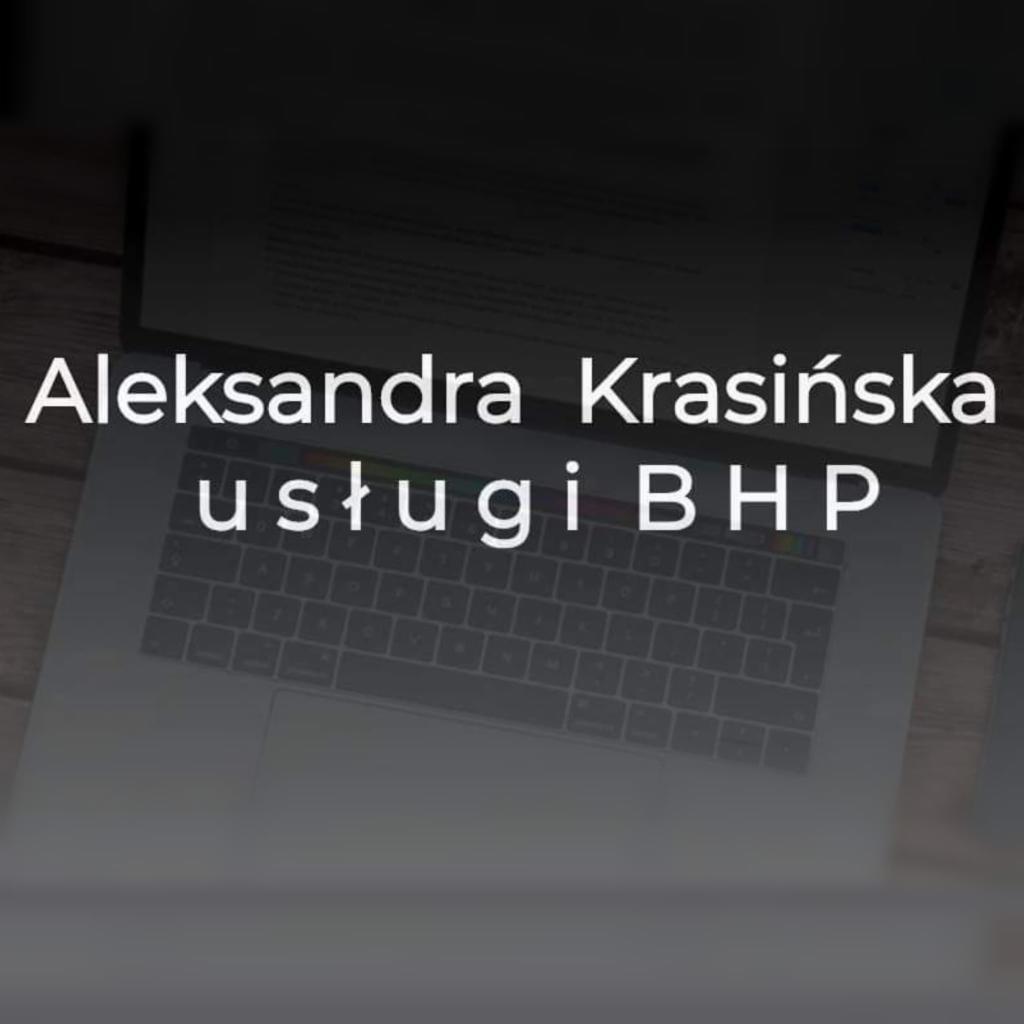 Laptop z wyświetlonym tekstem: Aleksandra Krasińska, usługi BHP. Widoczna klawiatura i fragment dokumentu w tle.