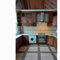 Zdjęcie aranżacji kuchni z brązowymi szafkami, białym blatem, płytkami w romby i pralką w zabudowie, widoczne z trzech różnych perspektyw.