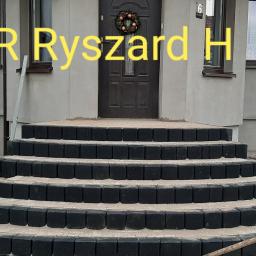Usługi budowlano remontowe RYSZARD HĘCIAK - Czterostopniowe schody wejściowe do domu, wykonane z czarnej kostki brukowej z jasną fugą, prowadzące do ciemnych drzwi z dekoracyjnym wieńcem.