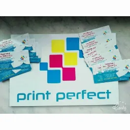 Stos wizytówek z nadrukiem na odzież firmy 'print perfect' z Jeziorka, ułożonych na białym tle z logo firmy w kolorach żółtym, różowym i niebieskim.