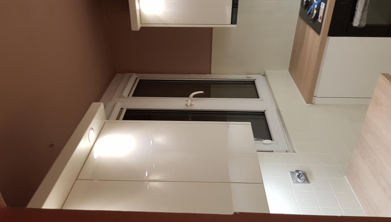 Biała kuchnia na wymiar z oknem, widok od dołu, jasne oświetlenie.