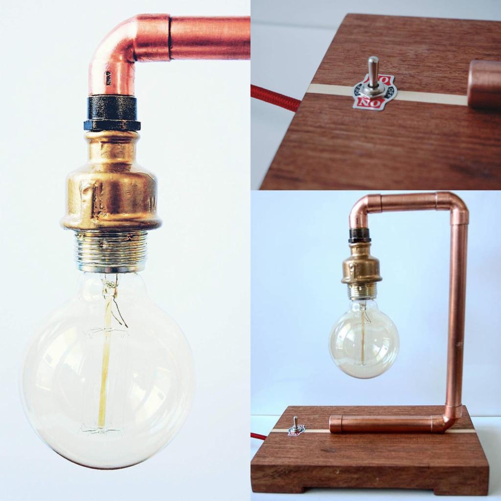 Lampa stołowa DIY z miedzianych rur i drewnianej podstawy, widoczne detale łączeń i włącznik z naklejką.