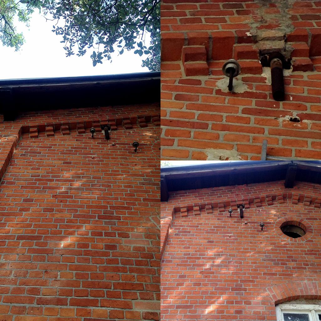 Ceglana elewacja budynku z elementami dekoracyjnymi z cegły, widoczne ceramiczne izolatory i fragment dachu, ujęcie z dołu.