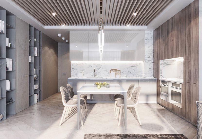 Wnętrze nowoczesnego mieszkania: biały stół z owocami, krzesła z jasną tapicerką, zabudowa kuchenna z marmurowym blatem i drewnianymi frontami, drewniany sufit lamelowy, podłoga z jasnej deski...