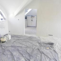 mateusz klimek - Pokój na poddaszu w trakcie malowania, zabezpieczona folią podłoga, widoczne puszki z farbą i gładzie na ścianach przed ostatecznym wykończeniem.