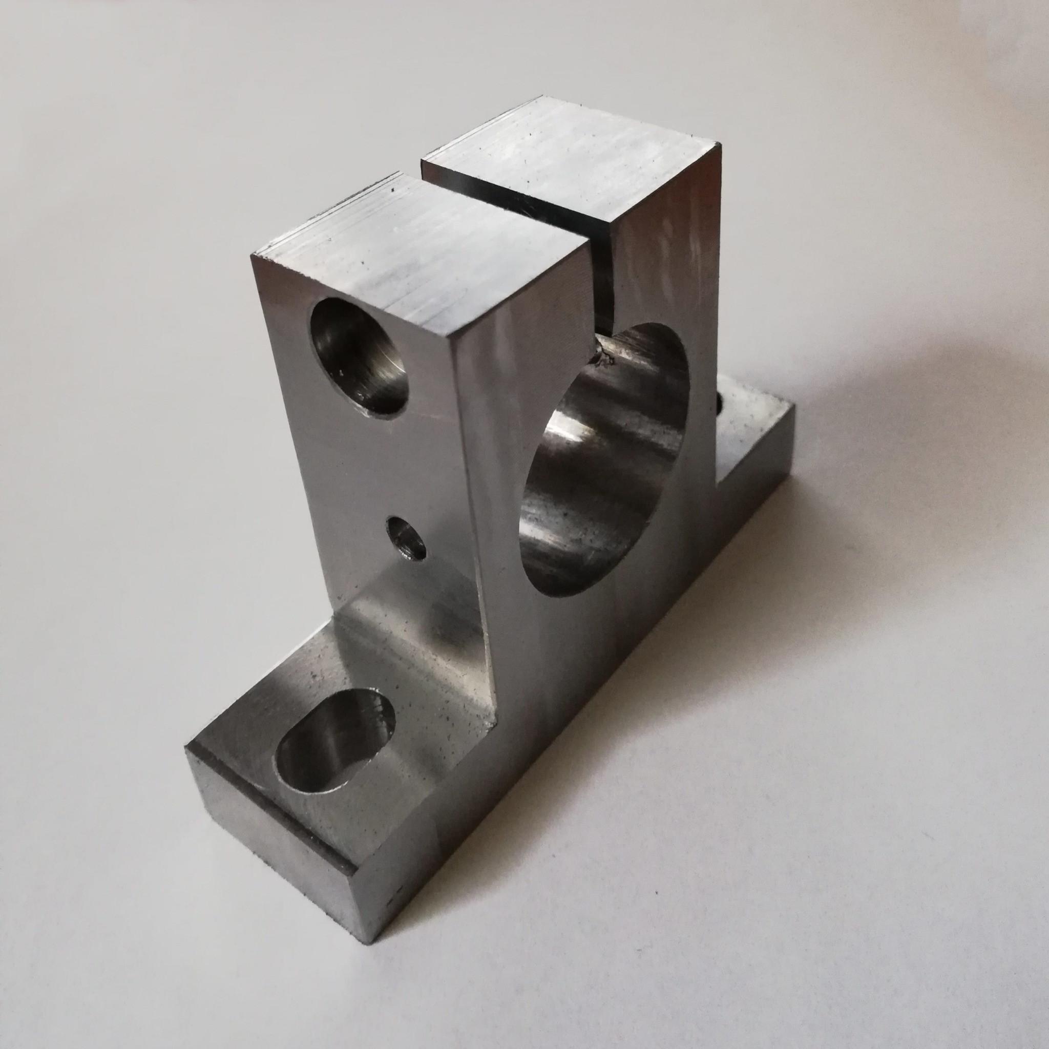 Szlifowany, metalowy uchwyt tokarski z trzema otworami o różnych średnicach, widoczny na białym tle.