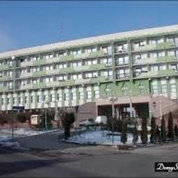 Przedsiębiorstwo Wielobranżowe MEGANT - Wielopiętrowy budynek z oknami PCV, jasną elewacją i zielonymi akcentami, sfotografowany w słoneczny dzień z lekko ośnieżonym terenem.