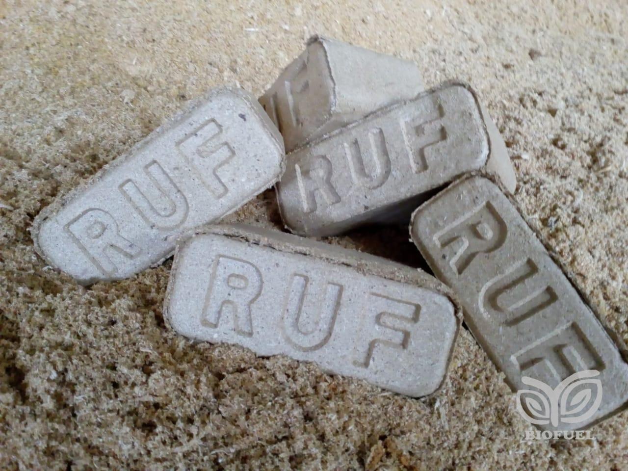 Kilka szarych kostek z wytłoczonym napisem RUF leżących na trocinach, w prawym dolnym rogu widoczne logo Biofuel.