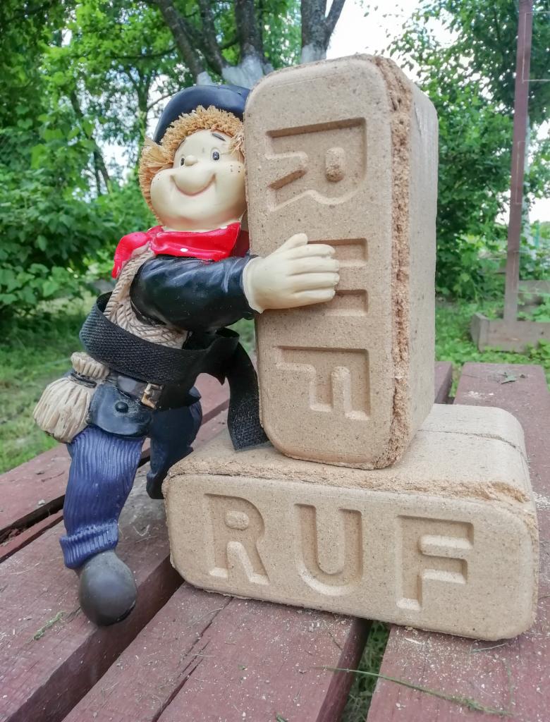 Figurka kominiarza obejmuje dwa ułożone jeden na drugim bloki z widocznym napisem RUF, na tle zieleni.