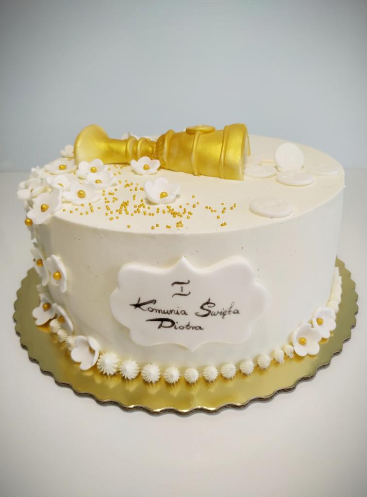 Tort komunijny z białym kremem, złotym kielichem na wierzchu, białymi kwiatkami i napisem 'I Komunia Święta Piotra' na dekoracyjnej tabliczce.