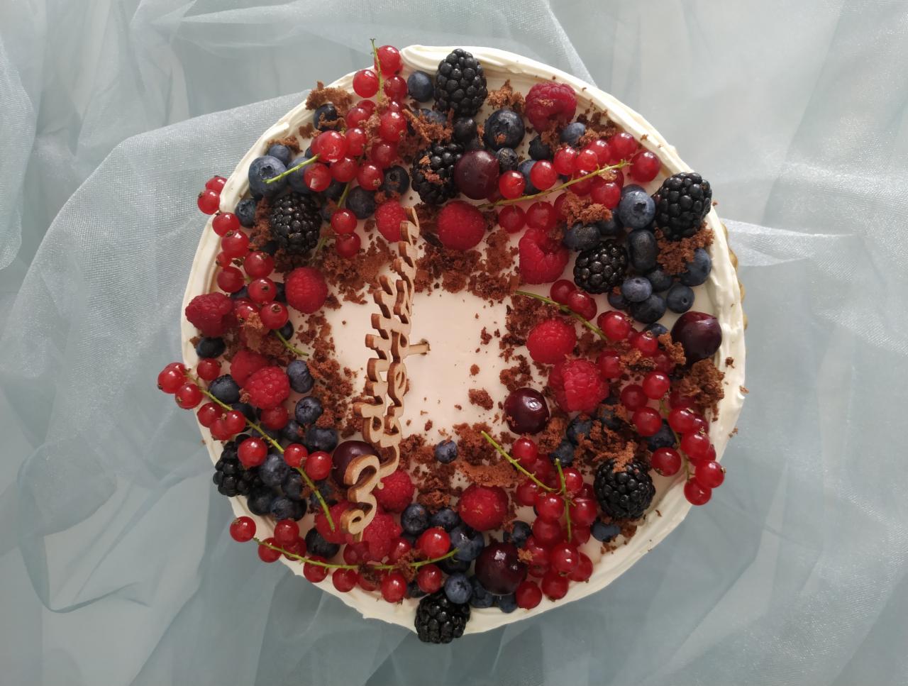 Tort udekorowany świeżymi malinami, jeżynami, borówkami, wiśniami i czerwoną porzeczką, posypany kruszonką czekoladową, z drewnianym napisem '30'