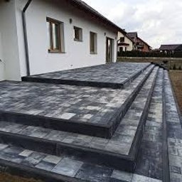 Perfect Home - Ułożona kostka brukowa na tarasie i schodach przed domem w Czerwionce-Leszczynach. Widoczne szare i czarne kostki tworzące wzór na powierzchni.