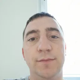 Portret mężczyzny na tle białego okna z widocznym zamkiem w ramie.