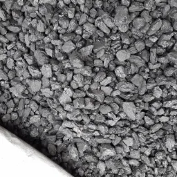 Kupa antracytu o nieregularnych kształtach, z fragmentem worka jutowego w lewym dolnym rogu, ukazująca strukturę i połysk węgla.