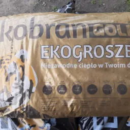 Worek ekogroszku Ekobran Gold o wadze 25kg, z widocznymi parametrami technicznymi i informacjami o producencie, leżący na szarym podłożu.