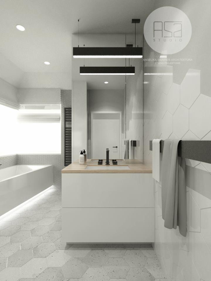 Nowoczesna łazienka z heksagonalnymi płytkami podłogowymi i ściennymi, minimalistyczną szafką pod umywalkę z drewnianym blatem, oraz wiszącymi lampami liniowymi.