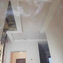 kgzabudowy@gmail.com - Skomplikowana konstrukcja sufitu podwieszanego z widocznymi elementami instalacji elektrycznej i fragmentem pomieszczenia z drzwiami w tle.