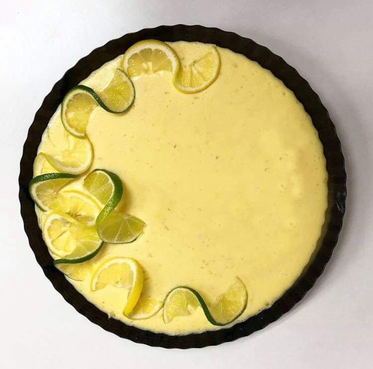 Tarta cytrynowa z dekoracją z plasterków cytryn i limonek ułożonych na brzegu, widok z góry.