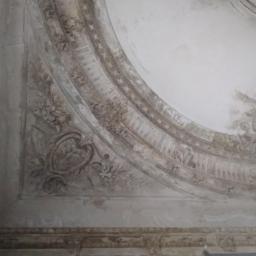 agata hermaszczuk - Fragment zdobionego sufitu z ornamentami w stylu klasycystycznym, widoczne ślady upływu czasu i braków w tynku.