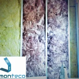 Ocieplenie ściany wełną mineralną w metalowym stelażu, widoczny fragment logo firmy Remonteco w lewym dolnym rogu.