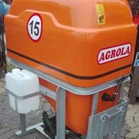 Pomarańczowy, metalowy pojemnik z napisem AGROLA, białą tabliczką z numerem 15 i białym zbiornikiem na płyn, zamontowany na metalowej ramie.