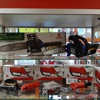 Półka w sklepie z ekspozycją pił łańcuchowych i nożyc do gałęzi, widoczne pudełka i narzędzia w kolorach czarnym, czerwonym i srebrnym.