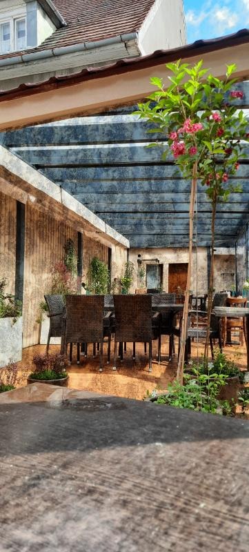 Zadaszony taras z rattanowymi meblami i kwitnącym drzewkiem ozdobnym, widok z perspektywy blatu stołu z widocznymi słojami drewna.