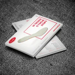 Stos ulotek reklamowych firmy Mazbit z kalendarzem, prezentujących logo i hasło 'W trosce o Twoje stopy' na szarym tle.