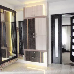 Nowoczesna aranżacja łazienki z zabudową meblową w odcieniach beżu i brązu z podświetleniem LED, widoczne drzwi z przeszkleniami i dekoracyjne mozaiki przy podłodze.