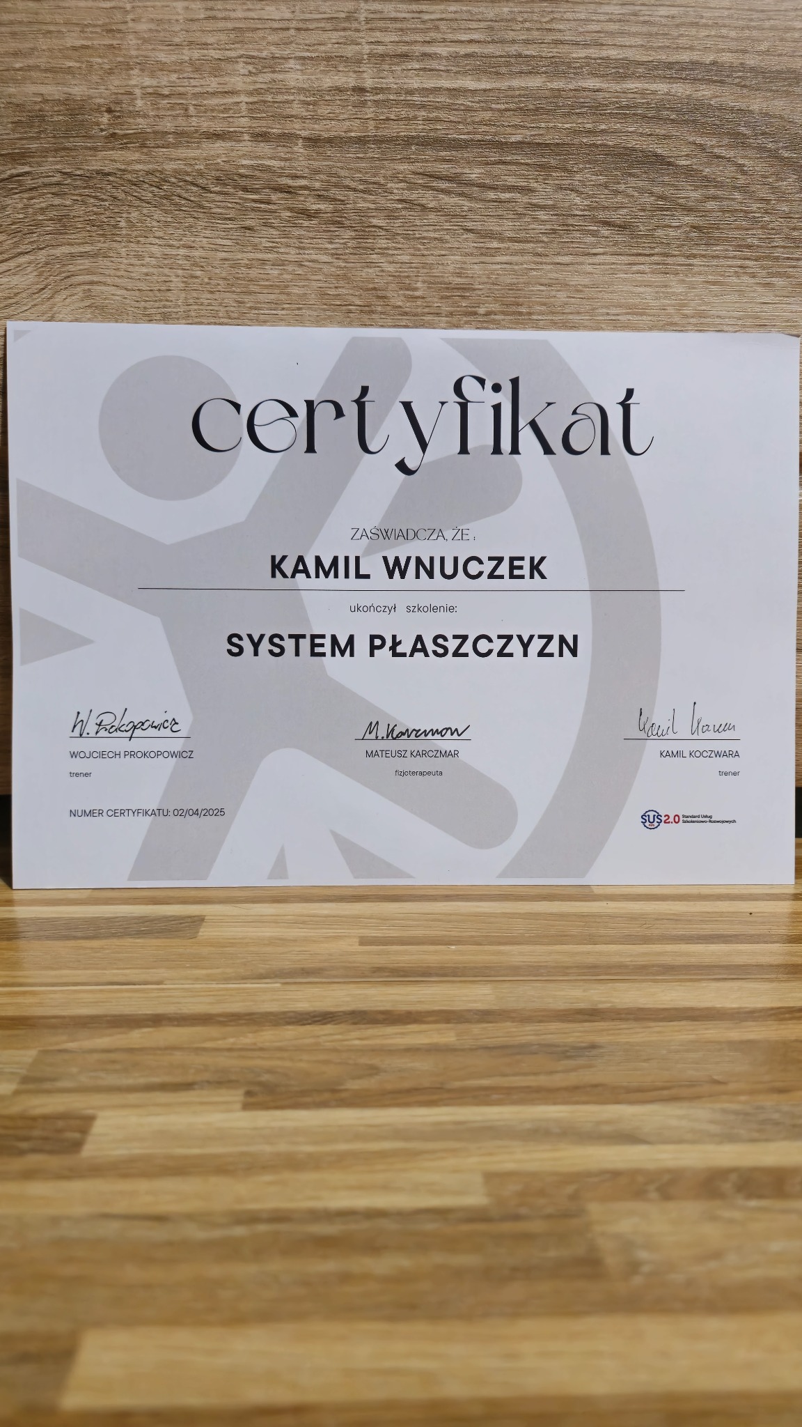 Certyfikat ukończenia szkolenia 'System Płaszczyzn' dla Kamila Wnuczka, podpisany przez Wojciecha Prokopowicza (trener), Mateusza Karczmara (fizjoterapeuta) i Kamila Koczwara (trener), z datą...