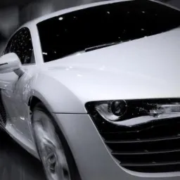 Dynamiczne ujęcie białego sportowego samochodu z rozmytym tłem, podkreślające jego aerodynamiczną sylwetkę i prędkość.